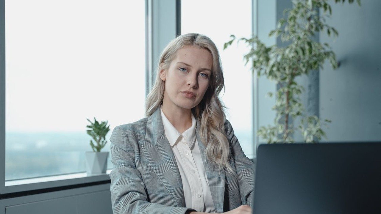 A professional woman in gray blazer working with confidence and focus at her desk